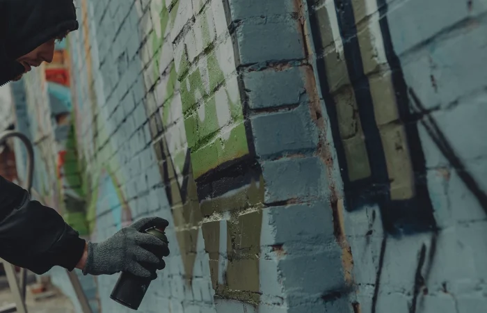 criminal mischief, spray painting walls, street artist painting colorful graffiti on wall