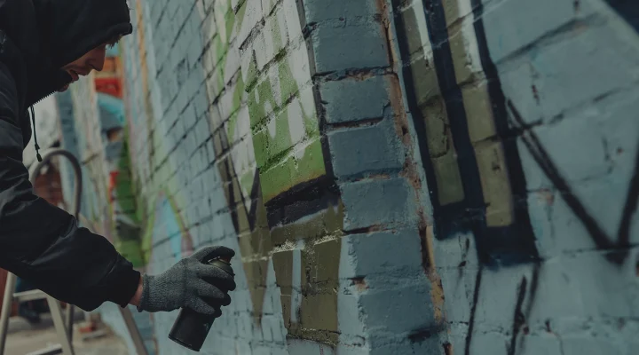 criminal mischief, spray painting walls, street artist painting colorful graffiti on wall