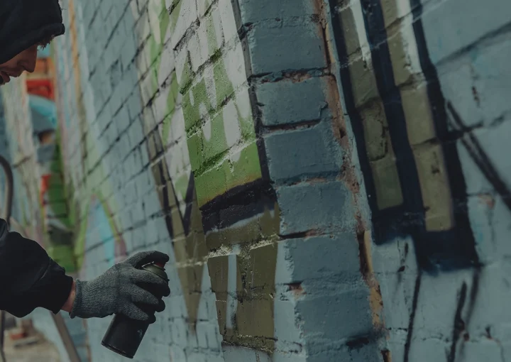 criminal mischief, spray painting walls, street artist painting colorful graffiti on wall