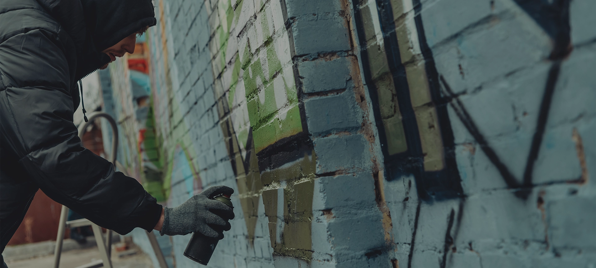 criminal mischief, spray painting walls, street artist painting colorful graffiti on wall
