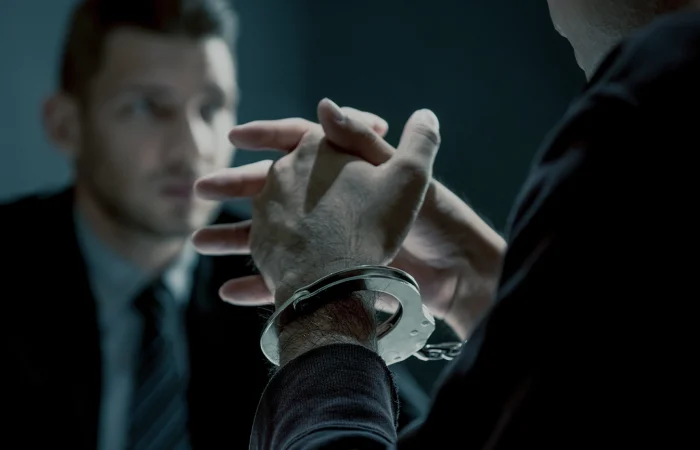 Criminal man with handcuffs being interviewed in interrogation room after committed a crime
