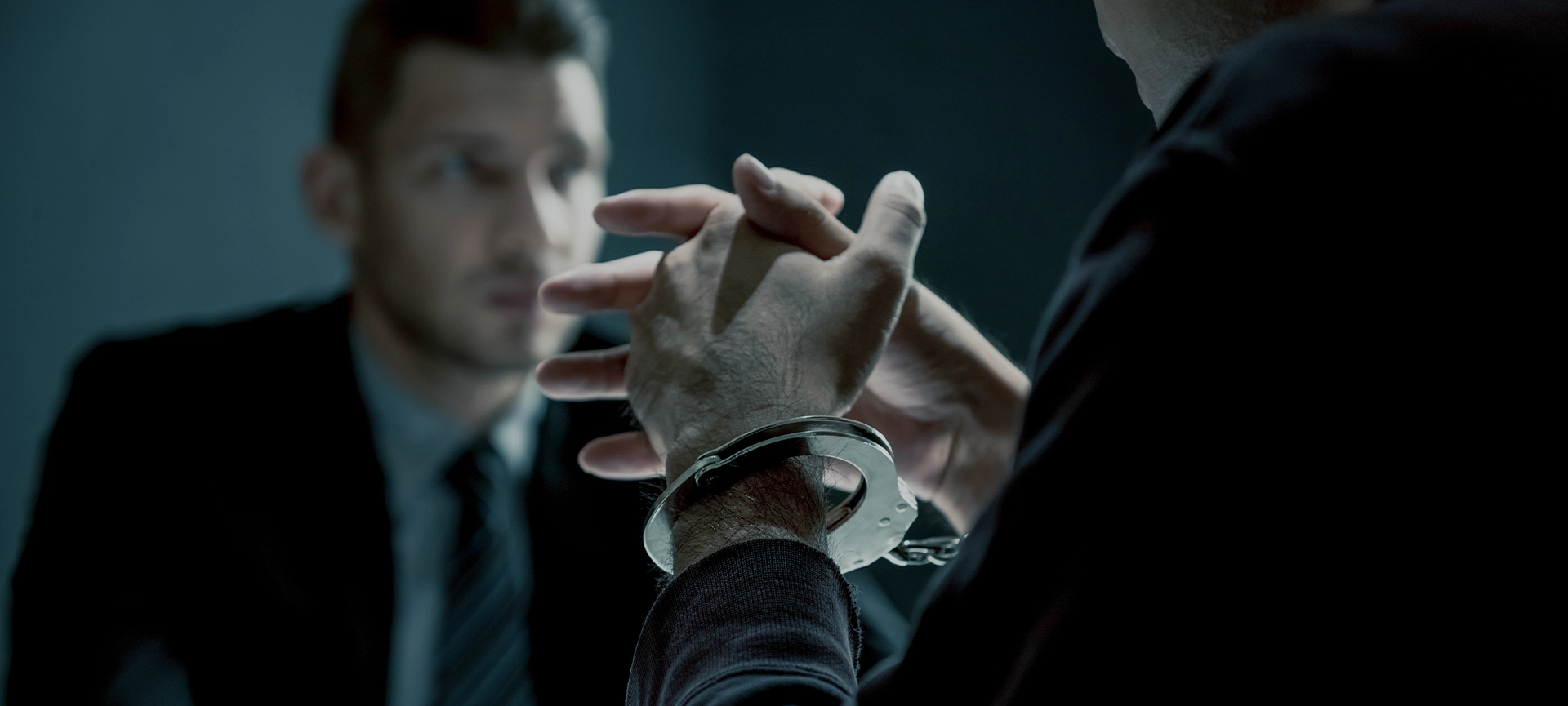 Criminal man with handcuffs being interviewed in interrogation room after committed a crime