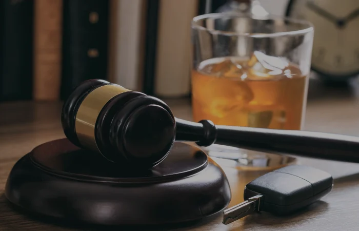 DUI concept. Law gavel, alcohol and car keys on a wooden desk, dark background