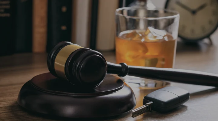 DUI concept. Law gavel, alcohol and car keys on a wooden desk, dark background