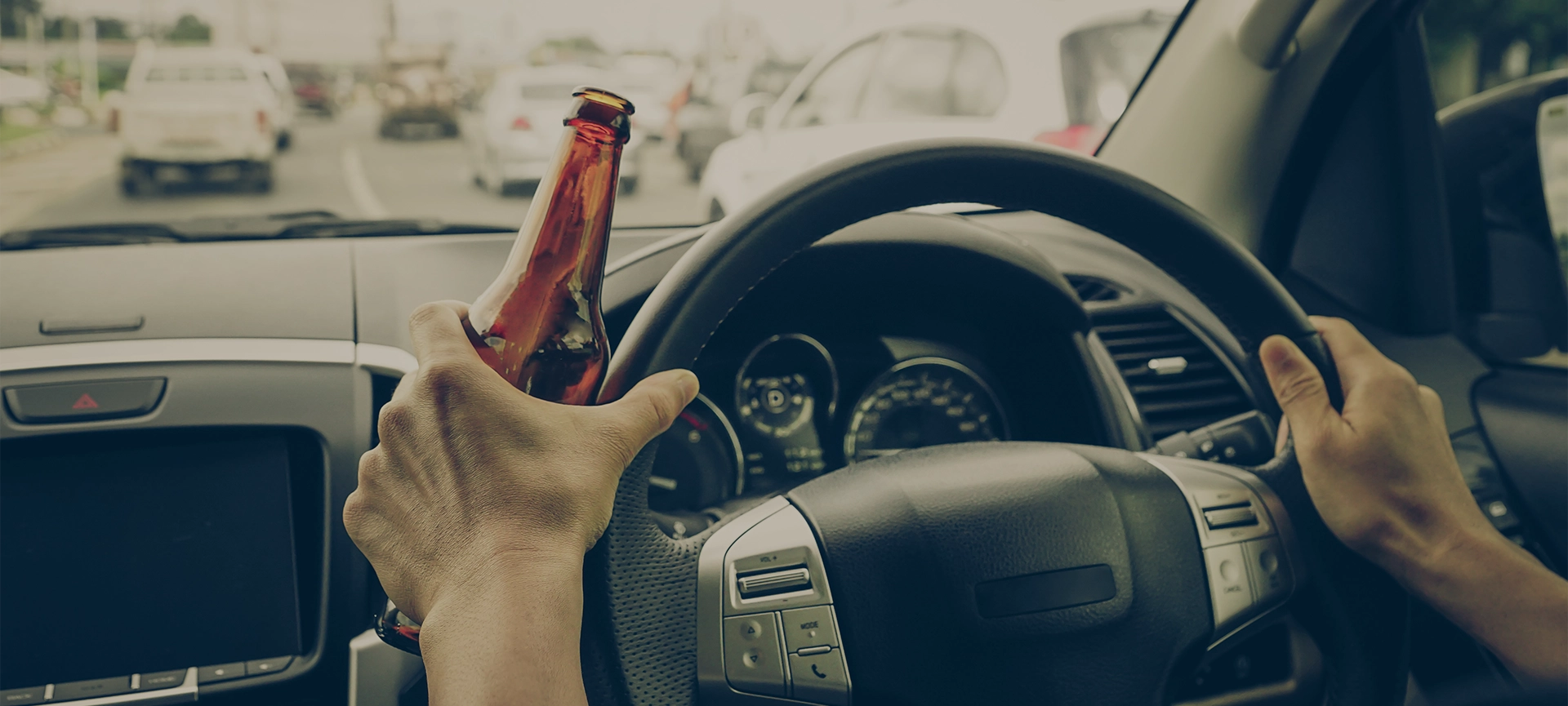 A driver holding alcoholic bottle while driving / Drunk driving concept