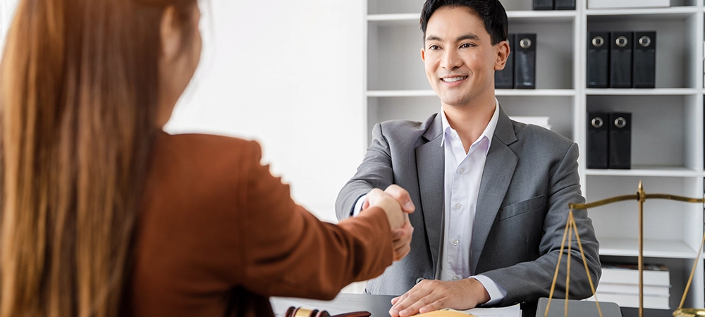 Lawyer shaking hands with client after discussing final contract agreement.