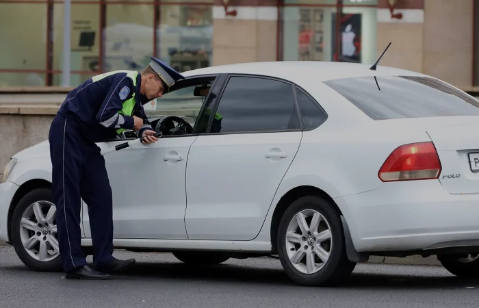Traffic police officer checks the documents of a car driver. Policeman patrol the city street in summer