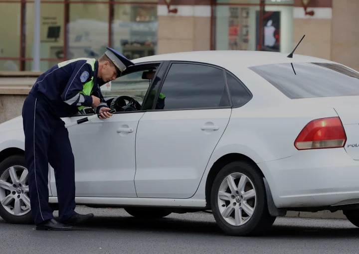Traffic police officer checks the documents of a car driver. Policeman patrol the city street in summer