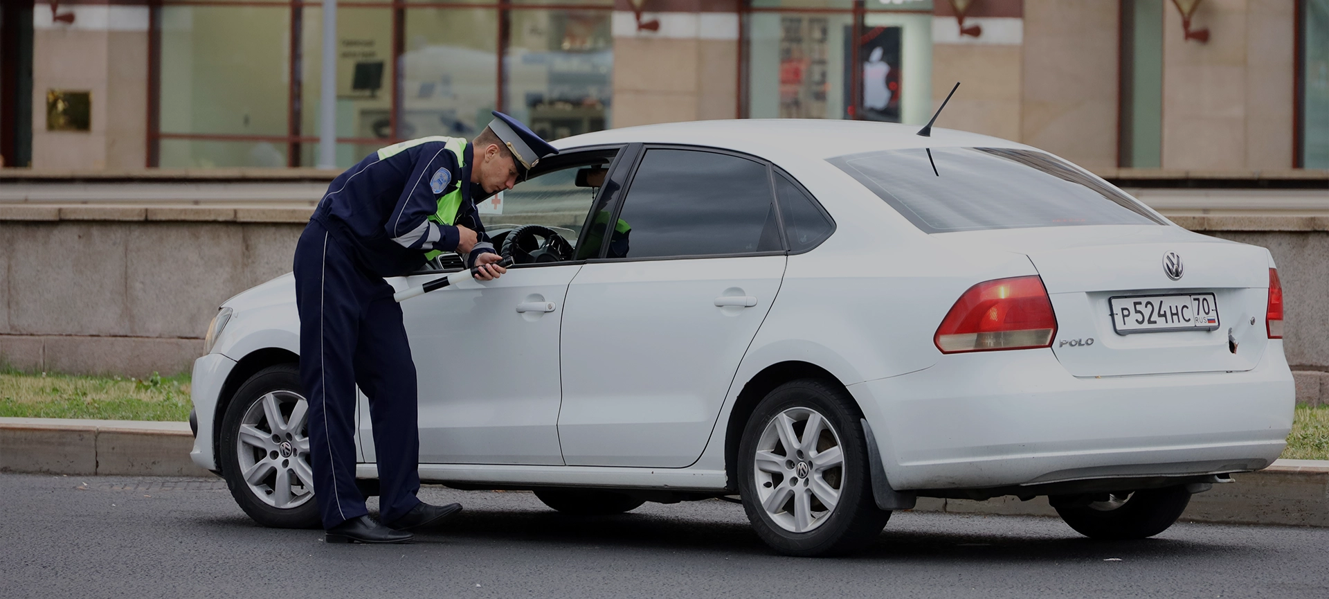 Traffic police officer checks the documents of a car driver. Policeman patrol the city street in summer