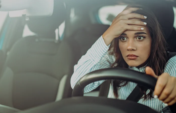 Angry woman driving a car. The girl with an expression of displeasure is actively gesticulating behind the wheel of the car. Angry business woman in a car. Stress girl in a car