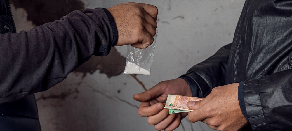 A person with money buys a dose of cocaine or heroin or other drug from a drug dealer.