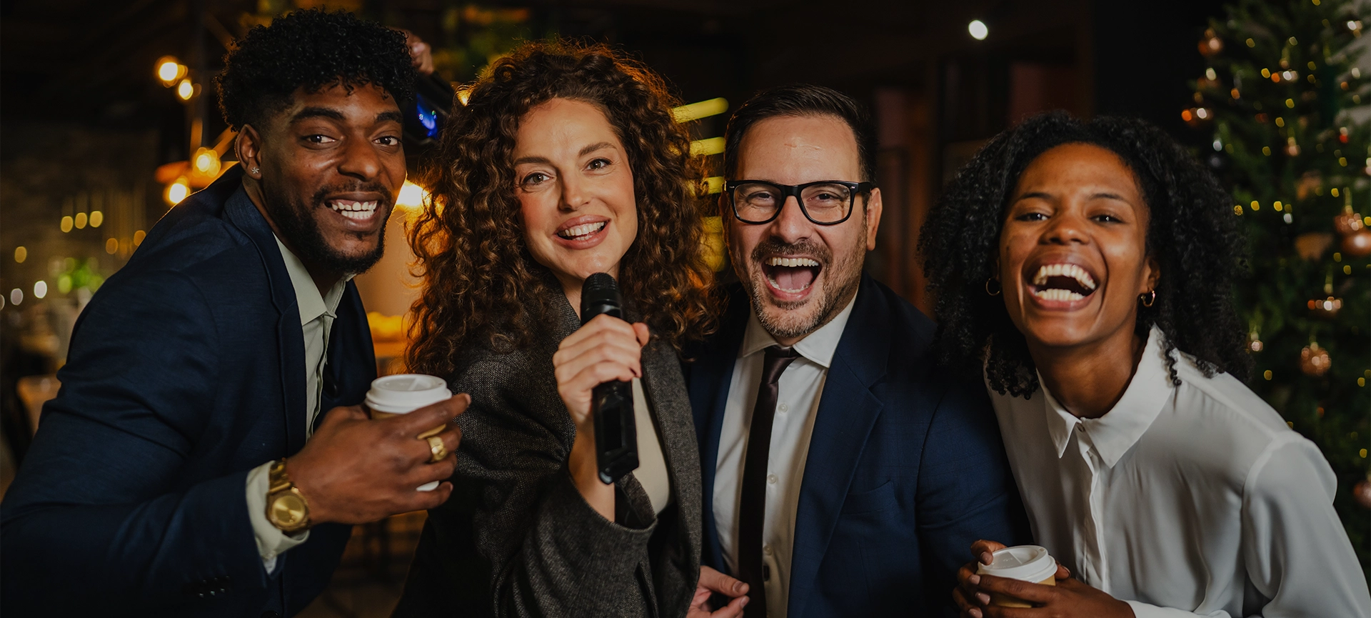 Diverse group of happy colleagues celebrating together at an office party, laughing and singing karaoke, enjoying festive team building during christmas holidays