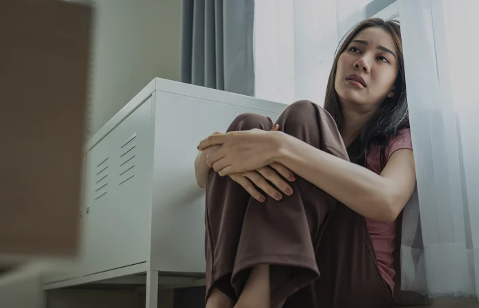 Asian young upset depressed woman sitting alone in living room at home.