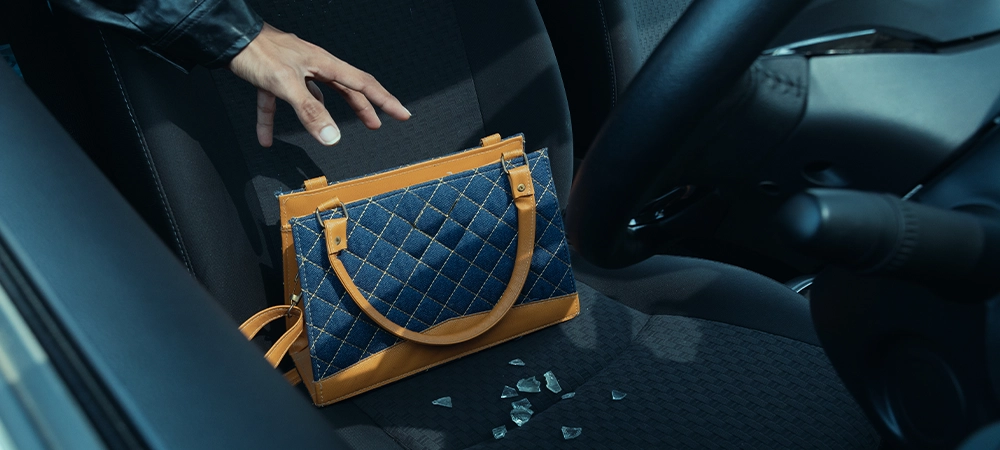 Robber breaking a car's windows to steal a woman bag.