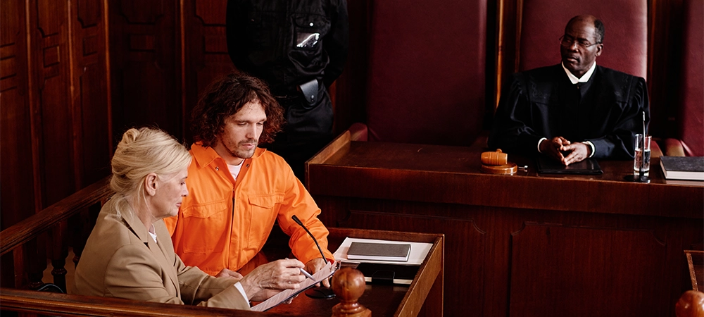 Confident mature attorney explaining case point to defendant in courtroom